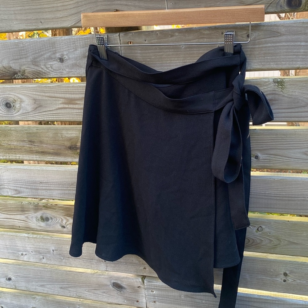 American Apparel wrap skirt in black. Hits above the knee.